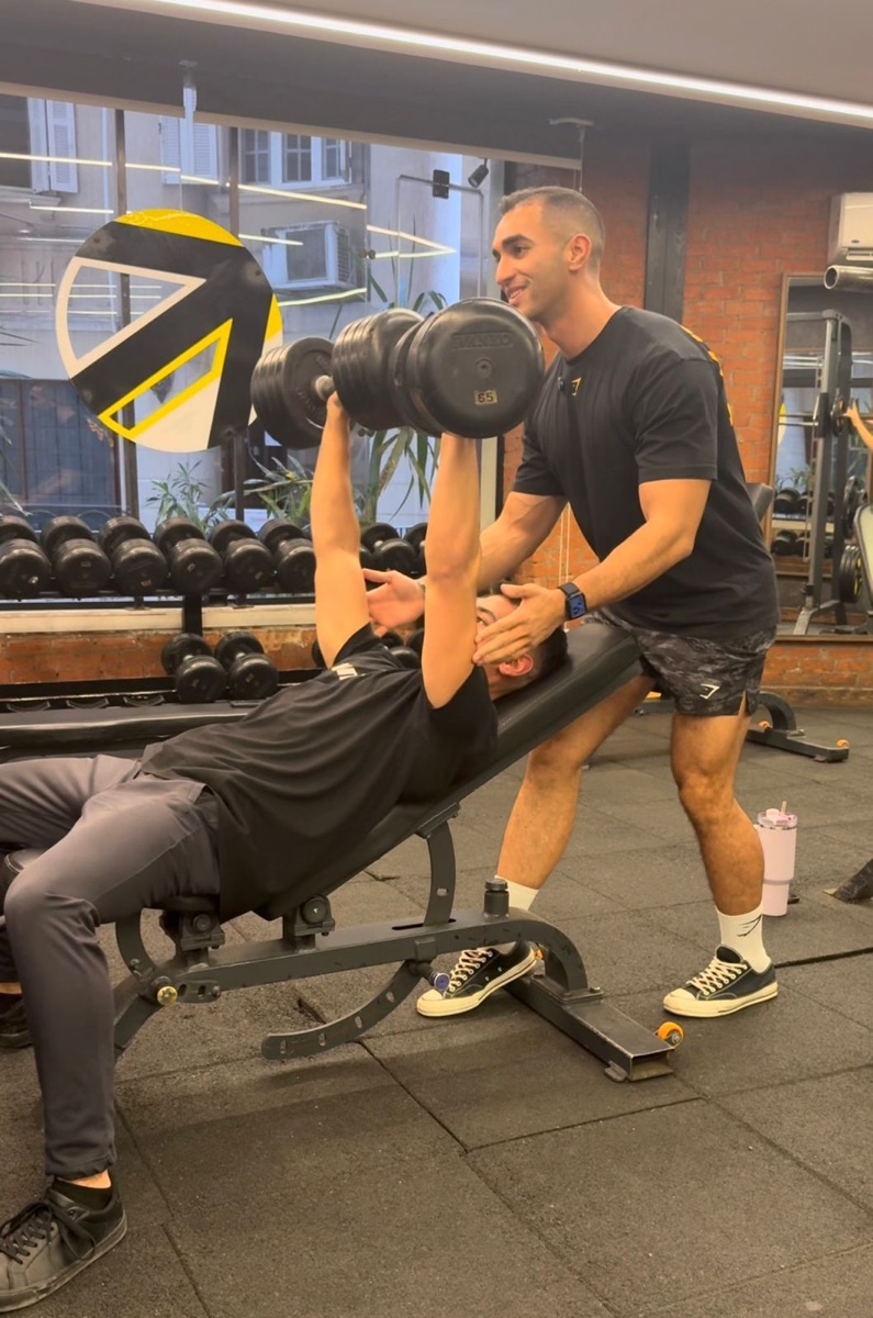 Muhammed coaching a client through a dumbbell press